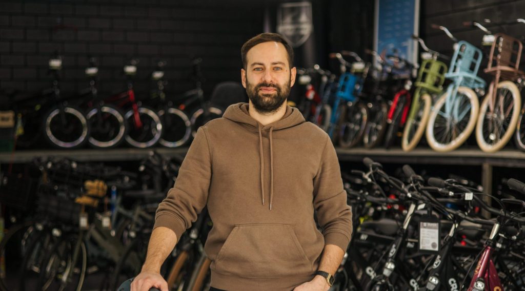 Ondernemer Superfietsen poseert met een fiets in zijn fietsenwinkel